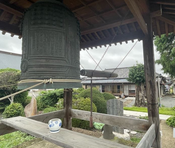 鐘越しに右手が築100年の古民家。左手が本堂。